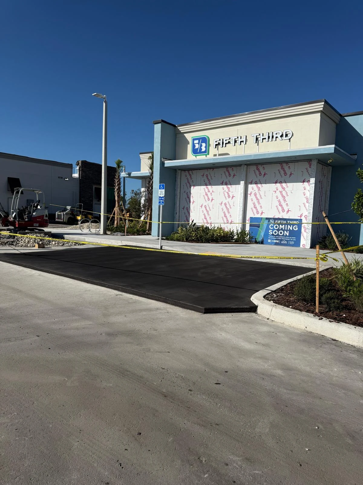 Fifth Third Bank storefront with a dark paved drive and construction equipment nearby
