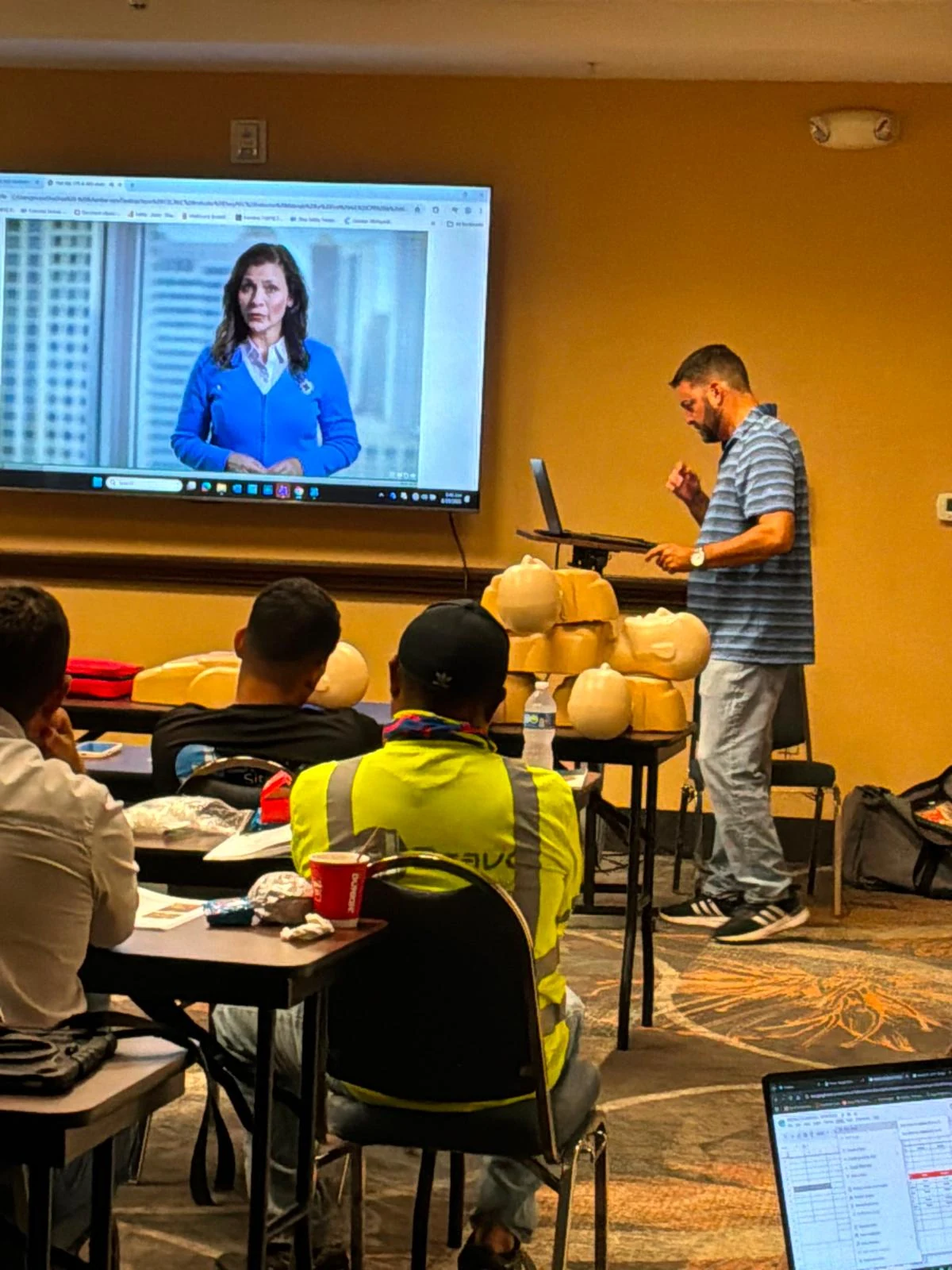 Instructor leading a classroom demonstration with CPR training manikins
