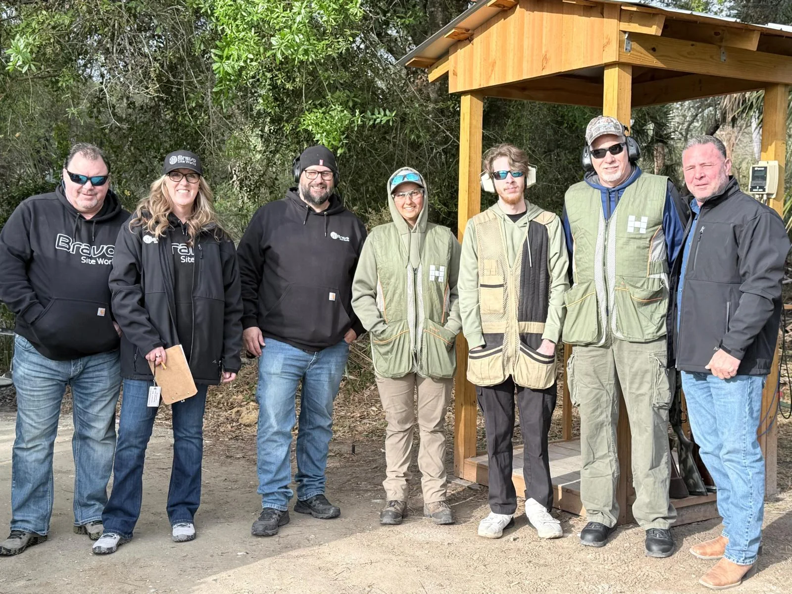 Small group gathered beside an outdoor shooting station at the 3rd Annual Bravo Shotgun Blast